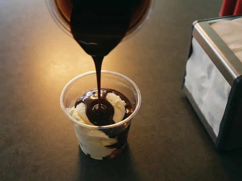 A mini hot fudge sundae in a clear plastic cup