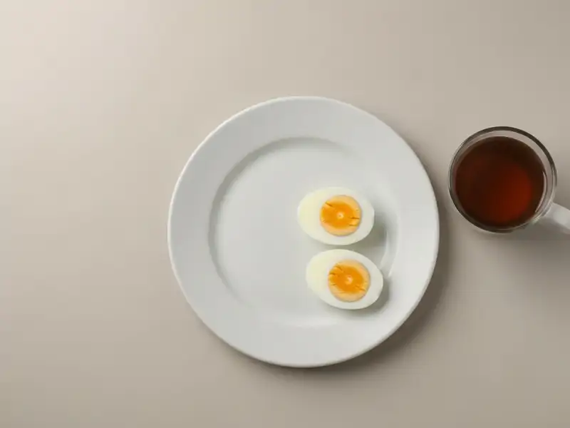 A single hard-boiled egg cut in half on a white plate