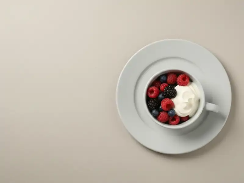 A small bowl of fresh mixed berries with a dollop of whipped cream