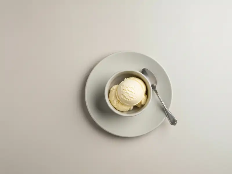 A single scoop of vanilla ice cream in a small bowl