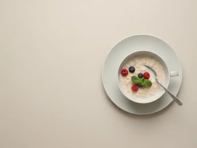 A bowl of oatmeal with berries and a spoon