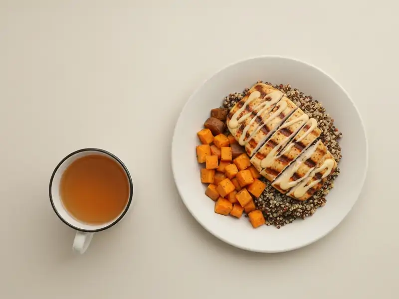 A single grilled chicken and quinoa bowl with sweet potatoes and dressing