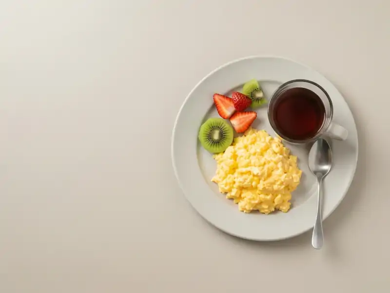 A plate of scrambled eggs with a side of fruit