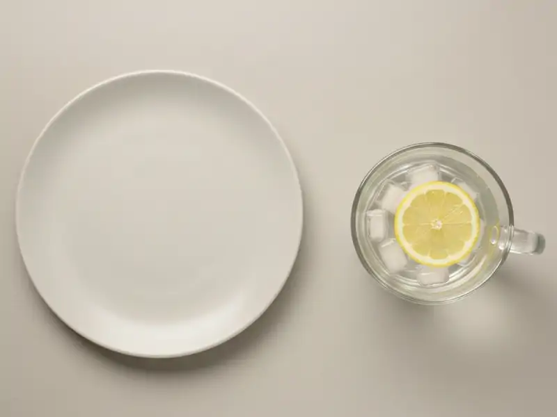 A clear glass of ice water with a lemon slice