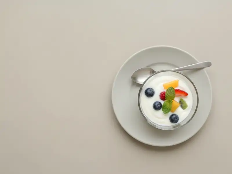 A small fruit and yogurt parfait in a glass bowl