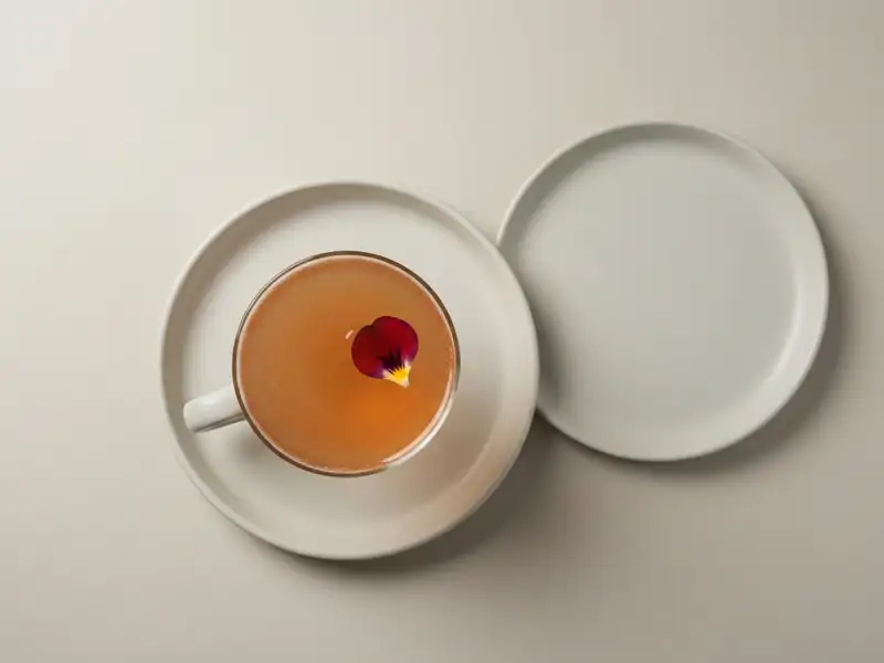 A fancy cocktail in a coupe glass, garnished with a single flower petal